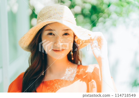 Young woman putting on a straw hat 114718549