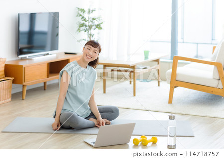 Female yoga stretching while looking at a computer Female yoga stretching while looking at a computer 114718757