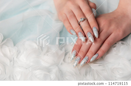 Elegant Hands Featuring Sparkling Ring and Blue Floral Manicure on Delicate White Fabric Elegant Hands Featuring Sparkling Ring and Blue Floral Manicure on Delicate White Fabric 114719115