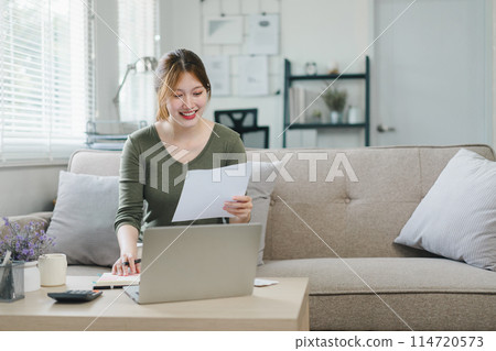 Happy asian young businesswoman calculate tax,counting paying domestic bills, e-banking, e-commerce, using laptop for calculation at home. Happy asian young businesswoman calculate tax,counting paying domestic bills, e-banking, e-commerce, using laptop for calculation at home. 114720573