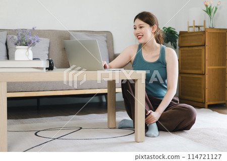 Young woman working on laptop at home during daytime in cozy living room. Young woman working on laptop at home during daytime in cozy living room. 114721127