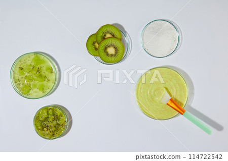 Exfoliating cream of fresh kiwi ingredient theme, with several dish of exfoliation and fresh kiwi featured on white table top and blank space in center for displaying product. Space for design Exfoliating cream of fresh kiwi ingredient theme, with several dish of exfoliation and fresh kiwi featured on white table top and blank space in center for displaying product. Space for design 114722542