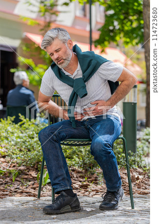 Mature man feeling sudden strong abdominal stomach ache gastritis problem poisoning diarrhea outdoor 114723680