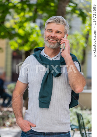 Mature tourist man having remote conversation online talk by smartphone unexpected good news gossip 114723699