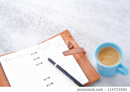 An image of a man working at his desk with a system organizer while drinking coffee with plenty of milk, or cafe au lait 114723980