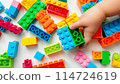 Kid hand building up a wall by stacking up the colorful wall block brick toy for banner, children sale promotion, flyer, online shop, poster, web, ads, and social media. Toddler Playing with colorful 114724619