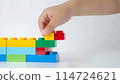 Kid hand building up a wall by stacking up the colorful wall block brick toy for banner, children sale promotion, flyer, online shop, poster, web, ads, and social media. Toddler Playing with colorful 114724621