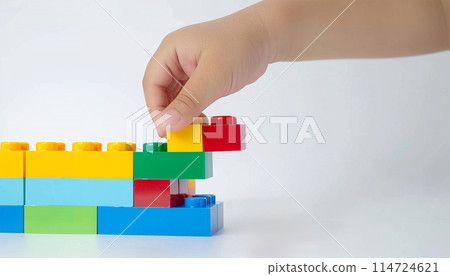 Kid hand building up a wall by stacking up the colorful wall block brick toy for banner, children sale promotion, flyer, online shop, poster, web, ads, and social media. Toddler Playing with colorful 114724621