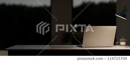 A back view image of a laptop computer on the table in a modern, dark room at night. A back view image of a laptop computer on the table in a modern, dark room at night. 114725709