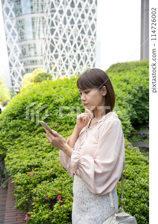 一名女子在人行道邊玩手機 114726002