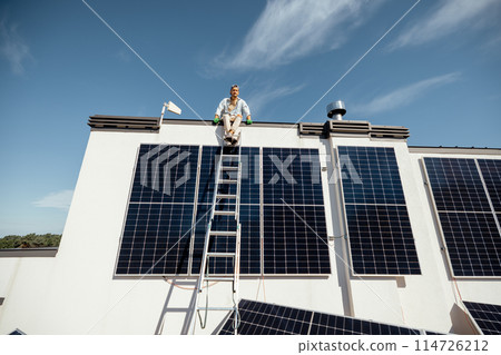 Man on rooftop of a private house with solar power station Man on rooftop of a private house with solar power station 114726212