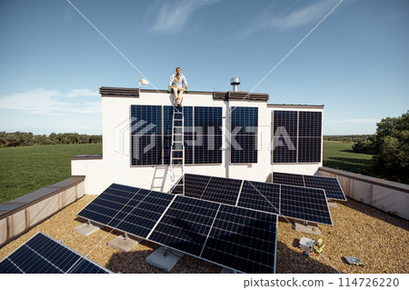 Man on rooftop of a private house with solar power station 114726220