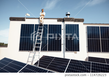 Man on rooftop of a private house with solar power station Man on rooftop of a private house with solar power station 114726223