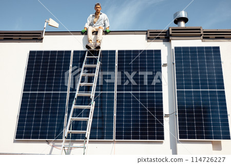 Man on rooftop of a private house with solar power station 114726227