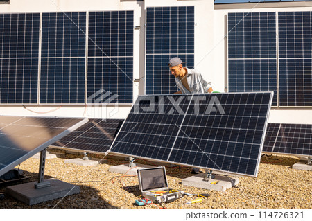 Man installing solar panels on the roof of his house Man installing solar panels on the roof of his house 114726321