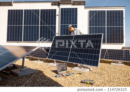 Man installing solar panels on the roof of his house 114726325