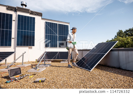 Man installing solar panels on the roof of his house 114726332