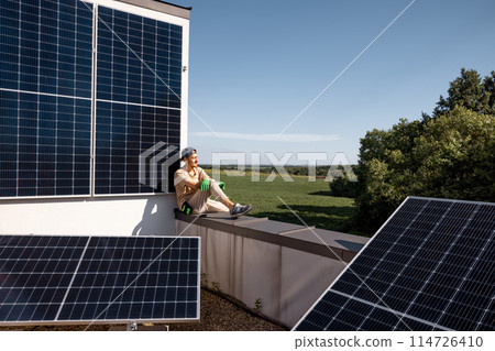 Man on a rooftop of his house with a solar power station Man on a rooftop of his house with a solar power station 114726410