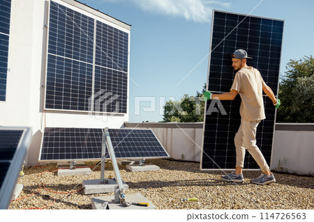 Man installing solar panels on a rooftop 114726563