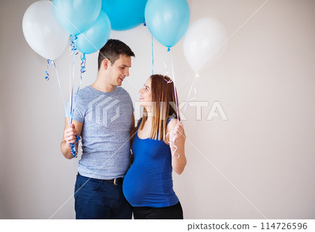 Pregnant woman and her partner holding blue balloons, expecting boy. Gender reveal. 114726596