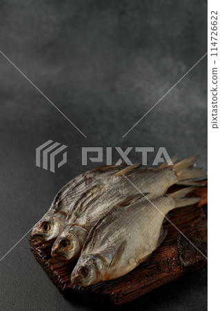 Dried bream fish on a cutting board on a black background 114726622