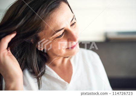 Portrait of beautiful mature woman with black hair and soft smile. 114726723