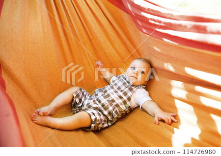 The baby is lying in a rocking hammock during a warm summer day. The baby is lying in a rocking hammock during a warm summer day. 114726980