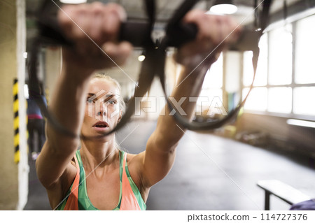 Beautiful sport woman doing suspension training, total resistance exercise. Routine workout for woman's physical and mental health. 114727376