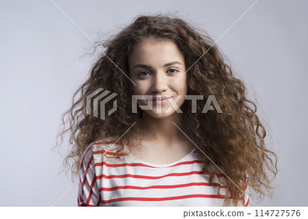 Portrait of a gorgeous teenage girl with curly hair. Studio shot, white background with copy space Portrait of a gorgeous teenage girl with curly hair. Studio shot, white background with copy space 114727576
