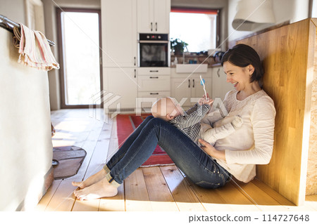 Mother playing with small baby, holding him on her knees. Unconditional paternal love, mother's Day concept. 114727648