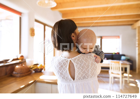 Mother holding small baby, carrying him around house. Unconditional paternal love, mother's Day concept. Mother holding small baby, carrying him around house. Unconditional paternal love, mother's Day concept. 114727649