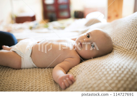 Portrait of cute little baby boy in diaper lying on bed, on back. Portrait of cute little baby boy in diaper lying on bed, on back. 114727691