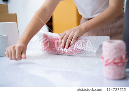 Small business entrepreneur woman packing product in mailing box for shipping from online store. Business online shipping and delivery concept. 114727755