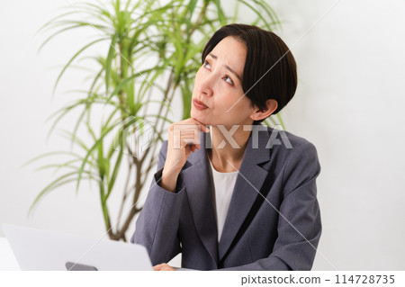 A young woman wearing a business suit and operating a laptop Business image 114728735