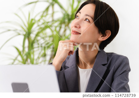 A young woman wearing a business suit and operating a laptop Business image 114728739