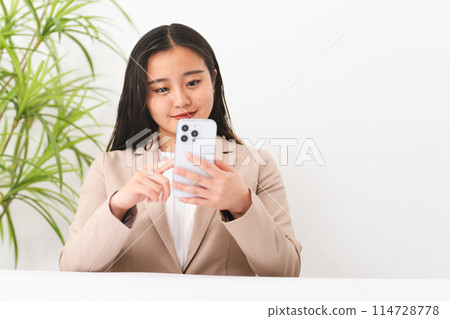 A young woman wearing a business suit operating a smartphone Business image 114728778
