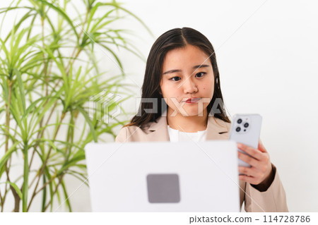 A young woman wearing a business suit and operating a laptop Business image 114728786