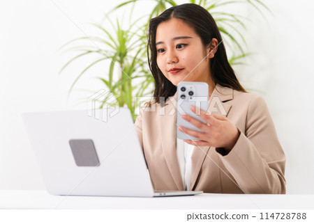 A young woman wearing a business suit and operating a laptop Business image 114728788