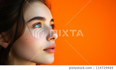 Portrait of a young beautiful girl on an orange background. 114729484