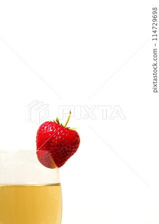 Red and ripe strawberry on glass with a yellow drink Red and ripe strawberry on glass with a yellow drink 114729698