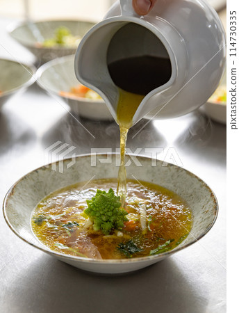 Pouring broth on fresh salad Pouring broth on fresh salad 114730335