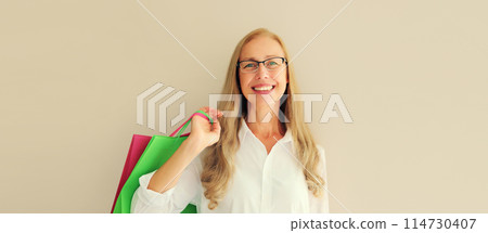 Portrait of beautiful happy smiling middle aged woman posing with shopping bags in eyeglasses 114730407