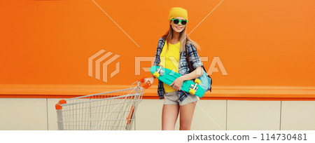 Stylish modern happy smiling young woman with shopping trolley cart and skateboard in the city Stylish modern happy smiling young woman with shopping trolley cart and skateboard in the city 114730481