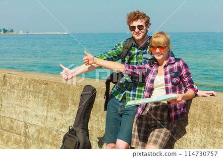 couple backpacker with map by seaside hitchhiking couple backpacker with map by seaside hitchhiking 114730757