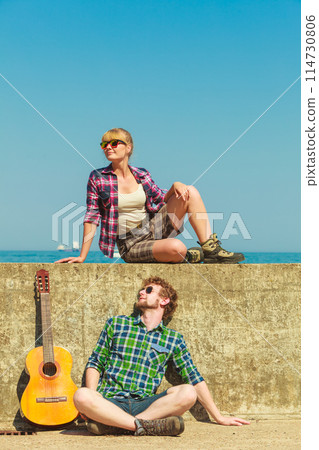 Young man playing guitar to his girlfriend by seaside Young man playing guitar to his girlfriend by seaside 114730806