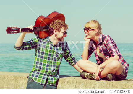 Young man playing guitar to his girlfriend outdoor Young man playing guitar to his girlfriend outdoor 114730828