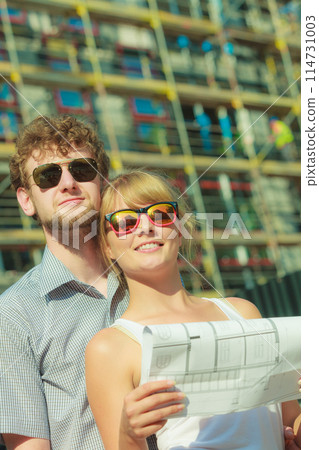 Couple on front of new house with blueprint project Couple on front of new house with blueprint project 114731003