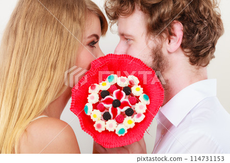 Couple kissing behind candy bunch flowers. Love. Couple kissing behind candy bunch flowers. Love. 114731153