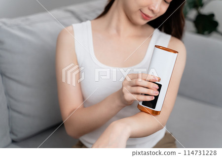 A beautiful woman is epilating and removing hair using an IPL laser hair removal epilator device. 114731228