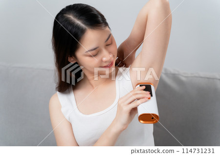 A beautiful woman is epilating her armpits using an IPL laser hair removal epilator device. A beautiful woman is epilating her armpits using an IPL laser hair removal epilator device. 114731231